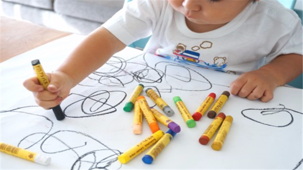 Young child drawing with chunky crayons